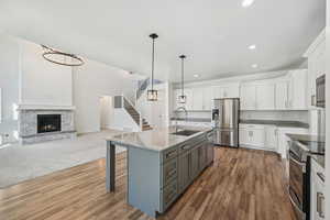 Kitchen with appliances with stainless steel finishes, sink, an island with sink, white cabinets, and dark wood-type flooring