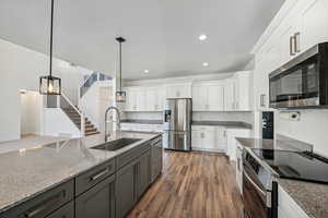 Kitchen with white cabinets, dark hardwood / wood-style flooring, sink, pendant lighting, and stainless steel appliances