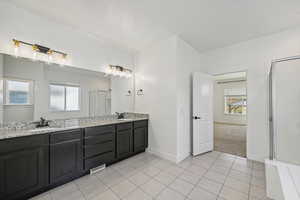 Bathroom featuring vanity, tile patterned flooring, and a shower with door