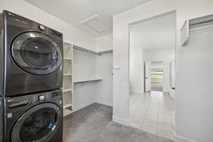 Washroom featuring light tile patterned flooring and stacked washer and clothes dryer