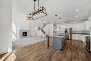 Kitchen with a center island with sink, white cabinetry, dark carpet, sink, and stainless steel appliances