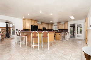 Kitchen featuring kitchen peninsula, black appliances, a wood stove, and a kitchen breakfast bar