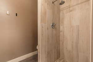 Bathroom with toilet, hardwood / wood-style flooring, and tiled shower