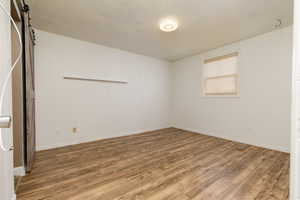 Empty room with a textured ceiling, a barn door, and hardwood / wood-style floors