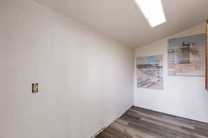 Spare room with vaulted ceiling and dark hardwood / wood-style flooring