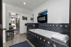 Bathroom featuring vanity, tiled tub, and hardwood / wood-style floors