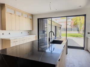 Kitchen with sink, a kitchen island with sink, light wood-type flooring, and light brown cabinets