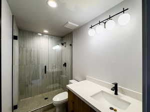 Bathroom with toilet, an enclosed shower, and vanity