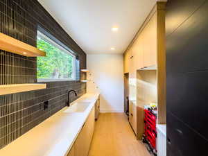 Kitchen featuring backsplash, sink, and light wood-type flooring