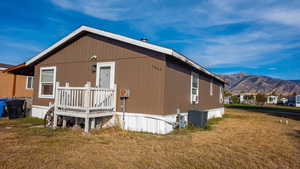 Exterior space featuring a front yard, a mountain view, and central AC unit