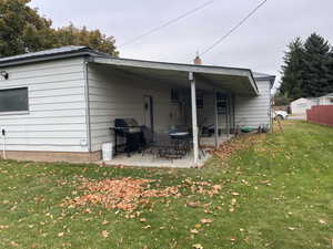 Rear view of property with a patio and a lawn