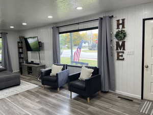 Living room with wood walls, a textured ceiling, and wood-type flooring