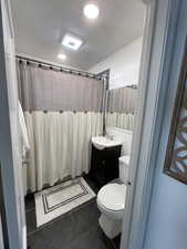 Bathroom featuring a textured ceiling, toilet, vanity, a shower with curtain, and tile patterned floors