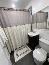 Bathroom featuring toilet, vanity, a shower with shower curtain, and tile patterned flooring