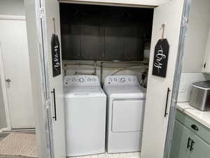 Laundry area featuring washing machine and dryer and cabinets