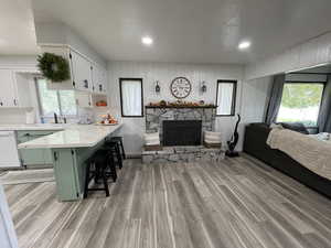 Kitchen featuring white cabinetry, white dishwasher, light wood-type flooring, and a breakfast bar area