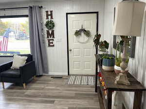 Entrance foyer with wood walls and hardwood / wood-style floors