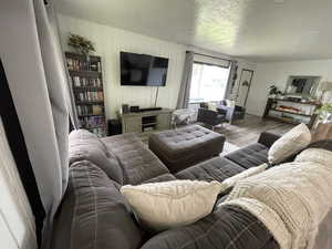 Living room with a textured ceiling, wooden walls, and wood-type flooring