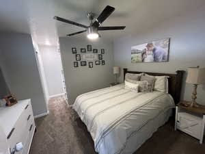 Bedroom featuring a textured ceiling, dark carpet, and ceiling fan