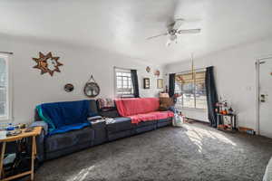 Carpeted living room featuring ceiling fan and a textured ceiling