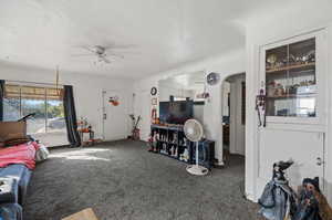 Carpeted living room featuring a textured ceiling and ceiling fan