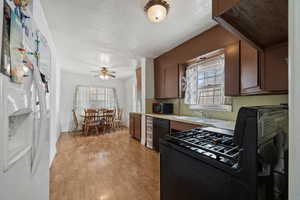 Kitchen with black appliances, plenty of natural light, ceiling fan, and light wood-type flooring