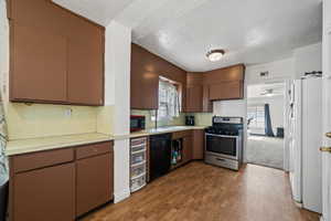 Kitchen with ceiling fan, sink, a textured ceiling, black appliances, and light wood-type flooring