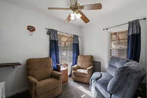 Sitting room featuring dark colored carpet and ceiling fan