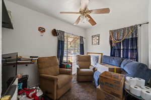 Living room with dark colored carpet and ceiling fan