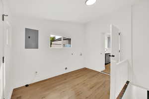 Empty room featuring electric panel, hardwood / wood-style flooring, and vaulted ceiling