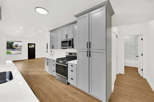 Kitchen featuring appliances with stainless steel finishes, light hardwood / wood-style flooring, and gray cabinetry