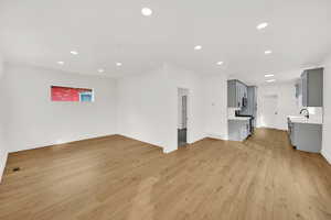 Unfurnished living room with sink and light wood-type flooring