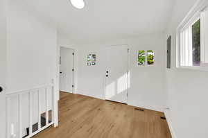 Foyer featuring electric panel, vaulted ceiling, and light hardwood / wood-style floors