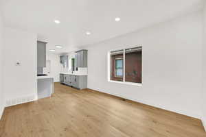 Unfurnished living room featuring a healthy amount of sunlight, sink, and light wood-type flooring