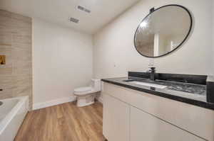 Full bathroom featuring vanity, shower with separate bathtub, wood-type flooring, and toilet