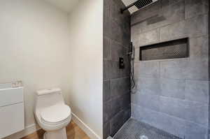 Bathroom with a tile shower, hardwood / wood-style flooring, toilet, and vanity