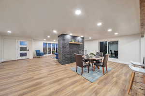 Dining room with a stone fireplace and light wood-type flooring