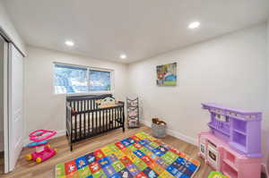 Bedroom with a closet, a nursery area, and wood-type flooring