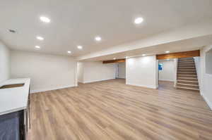 Basement featuring sink and light hardwood / wood-style flooring