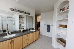 Bathroom featuring vanity, a textured ceiling, walk in shower, and built in features