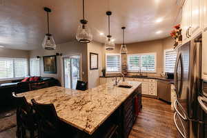 Gourmet kitchen featuring real oak flooring, beautiful knotty alder off white cabinets,  a wealth of natural light, stainless steel appliances, and a stunning granite island with sink