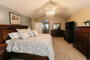 Bedroom featuring ceiling fan, a textured ceiling, vaulted ceiling, and light colored carpet