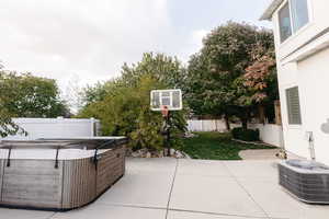 View of patio with central air condition unit and a hot tub