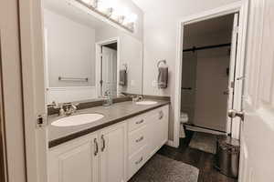 Bathroom with vanity, toilet, hardwood / wood-style flooring, and tiled shower