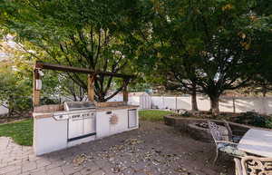 View of patio with area for grilling, sink, and a fire pit