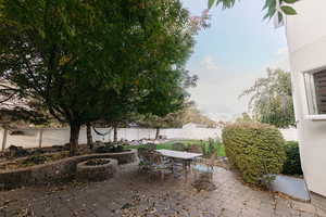 View of patio with an outdoor fire pit nicely shaded by mature trees and a great area for hosting large gatherings