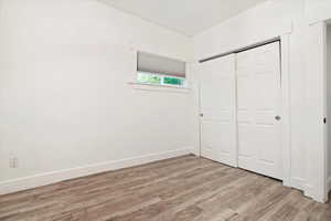 Unfurnished bedroom with light hardwood / wood-style flooring and a closet