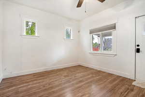 Empty room featuring ceiling fan, wood-type flooring, and plenty of natural light