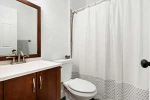 Bathroom with vanity, a shower with shower curtain, and toilet