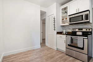 Kitchen featuring light hardwood / wood-style flooring, white cabinetry, and stainless steel appliances